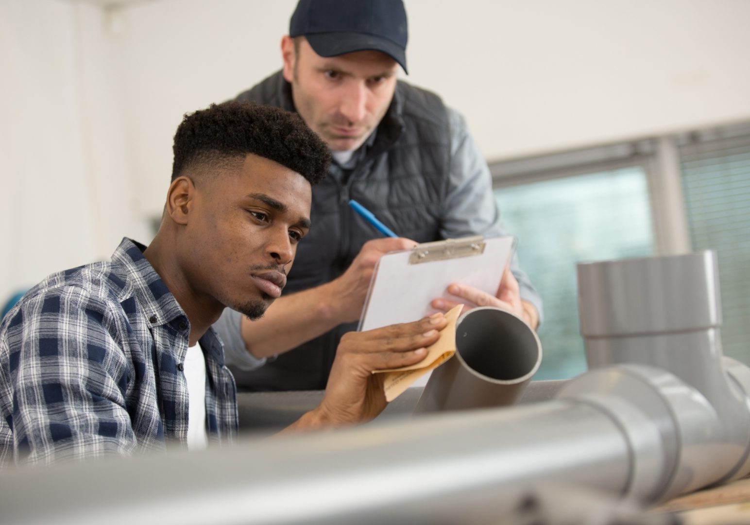 supervisor assessing trainee assembling pipe fittings