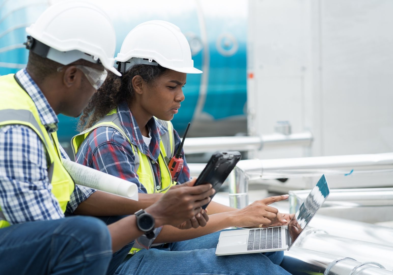 Male and female engineer worker working with laptop computer discuss and inspecting structure of building at rooftop of building at construction site