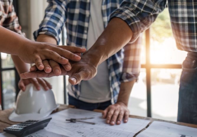 A team of engineers who successfully planned work on a modern home construction project shook hands and congratulated the team on their success..