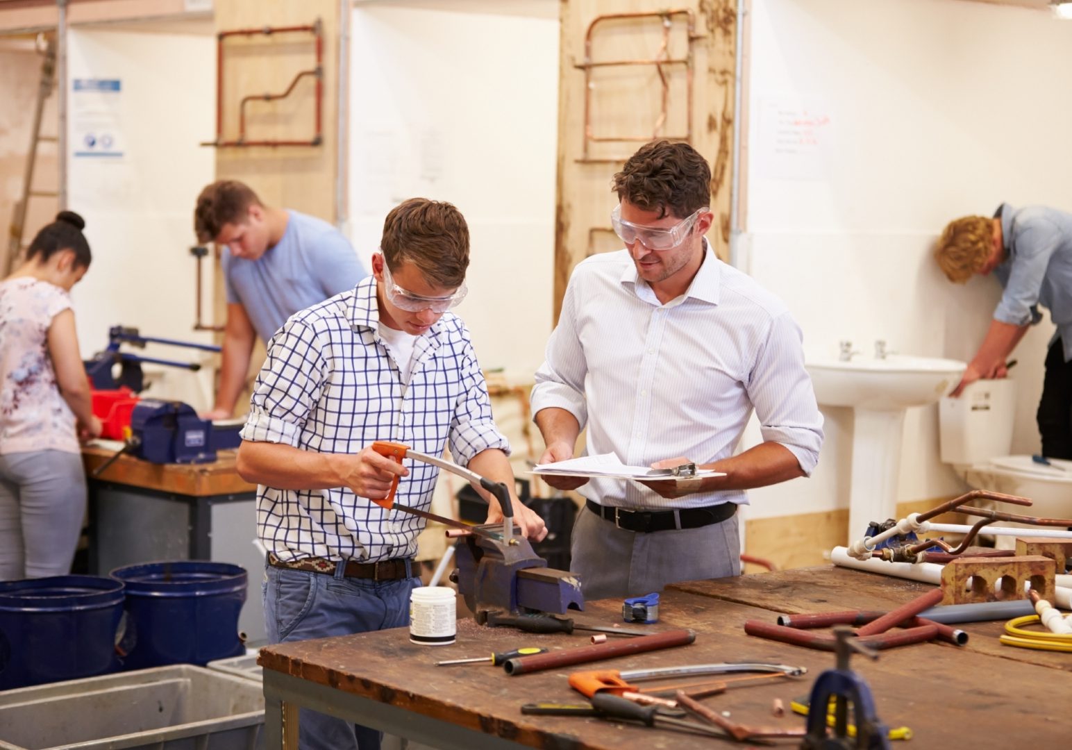 Teacher Helping College Students Studying Plumbing